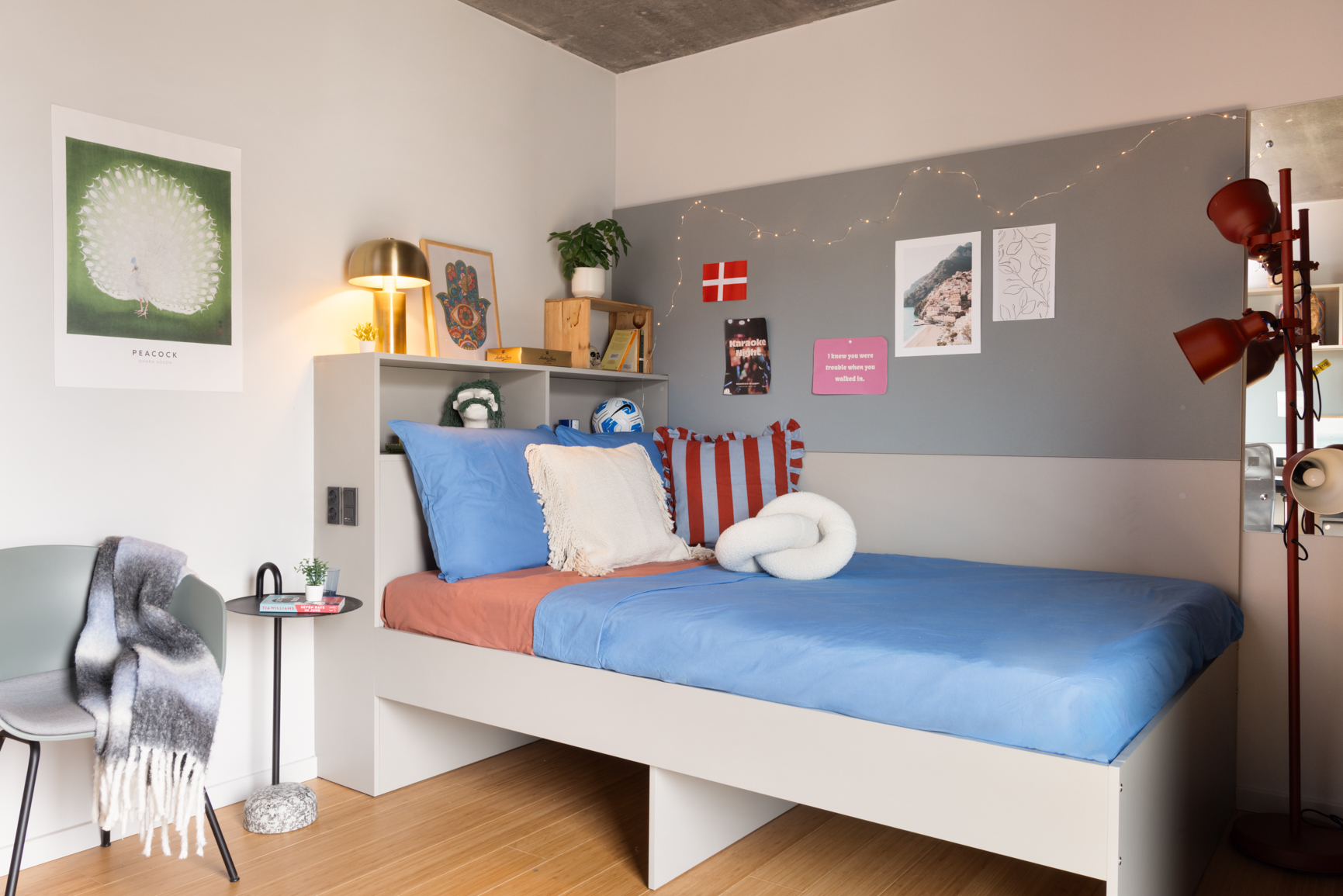 The Giant Studio with 140cm bed, shelving above the bed and corner chair in Basestack Living student accommodation and apartments to rent in Copenhagen