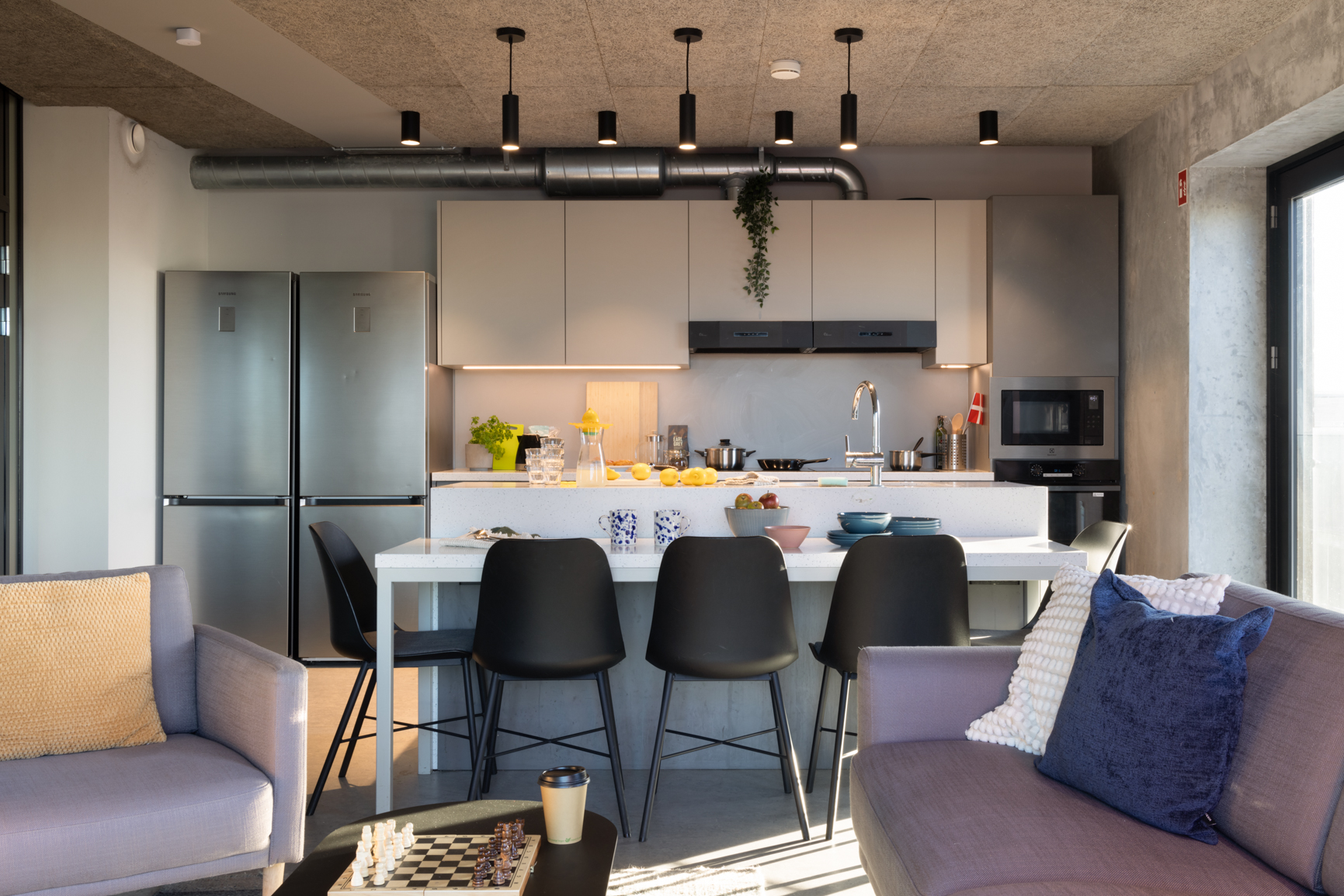 Landscape shot of common kitchen island and living area in Basestack Bryggen student accommodation and apartments to rent in Copenhagen