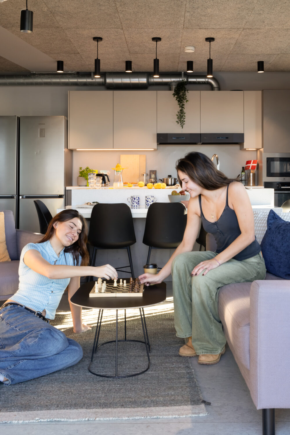 Two resident sat on sofa in common kitchen playing chess in BaseStack student accommodation and apartments to rent in Copenhagen
