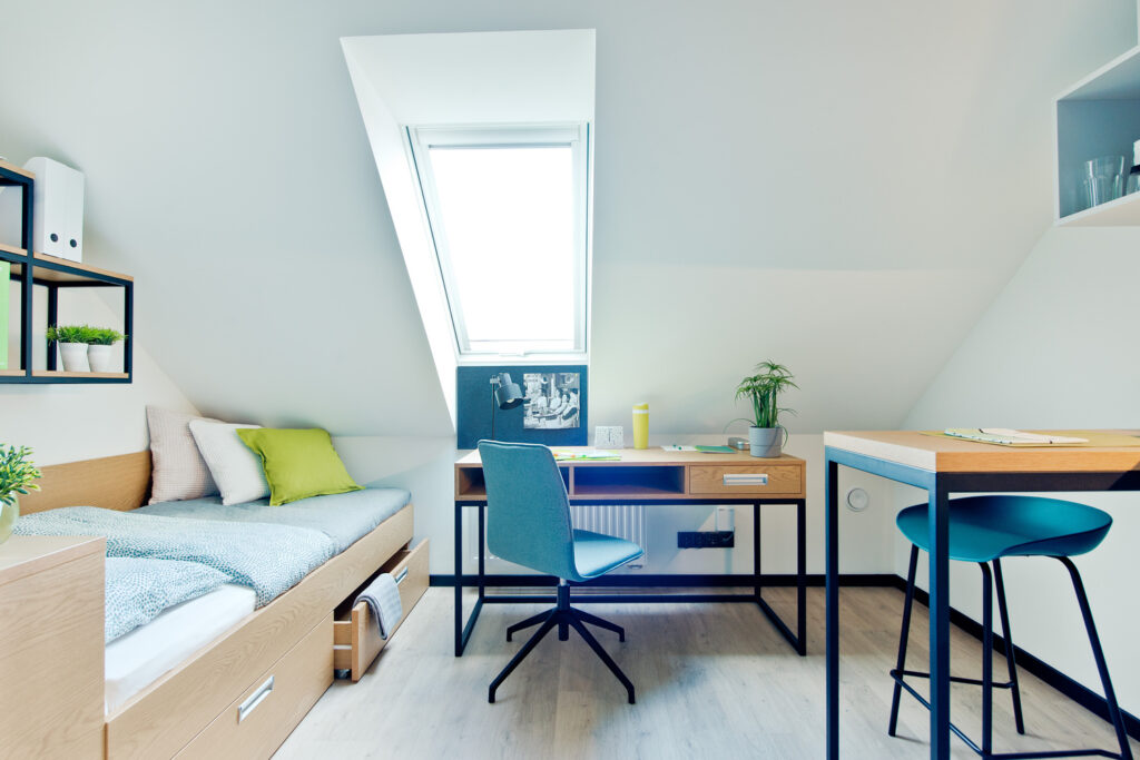 Bright attic studio at Gdansk Center with a skylight above the desk, a single bed and a compact breakfast counter.