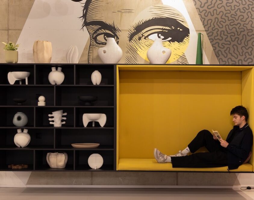 Built-in yellow window seat in the reception area, framed by black display shelving and large monochrome wall art.