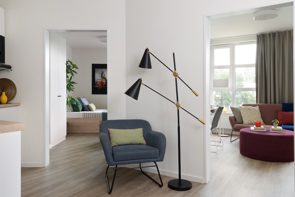 Blue lounge chair and geometric lamp positioned between two connected studio areas.