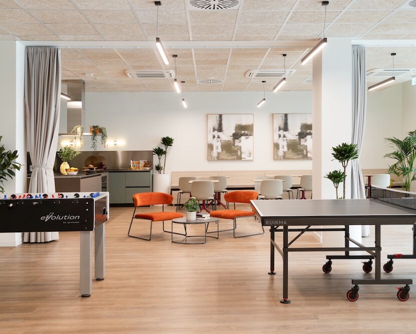 Large communal space with coffee tables and lounge seating, table tennis and foosball table at Tribera student accommodation in Milan.