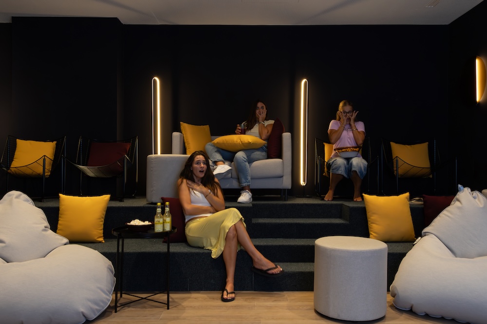 Residents seated in a tiered cinema room at Tribera student accommodation in Milan.