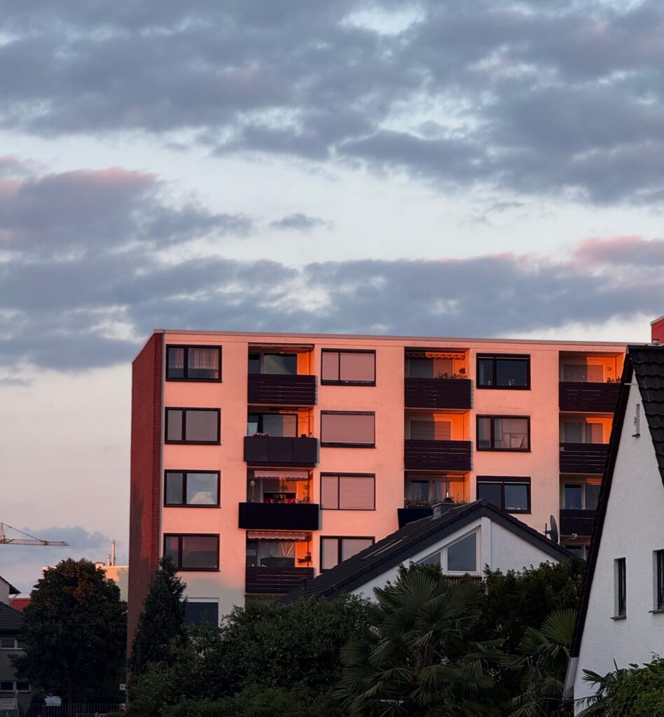 Top floors of a building with balconies in rays of a setting sun.
