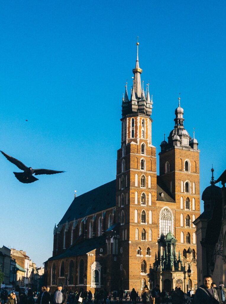 St. Mary's Church in Kraków on a sunny day against a blue sky with a bird flying by.