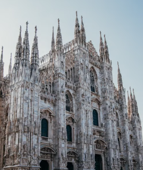 View of the front wall of the Milan Cathedral against a blue sky.