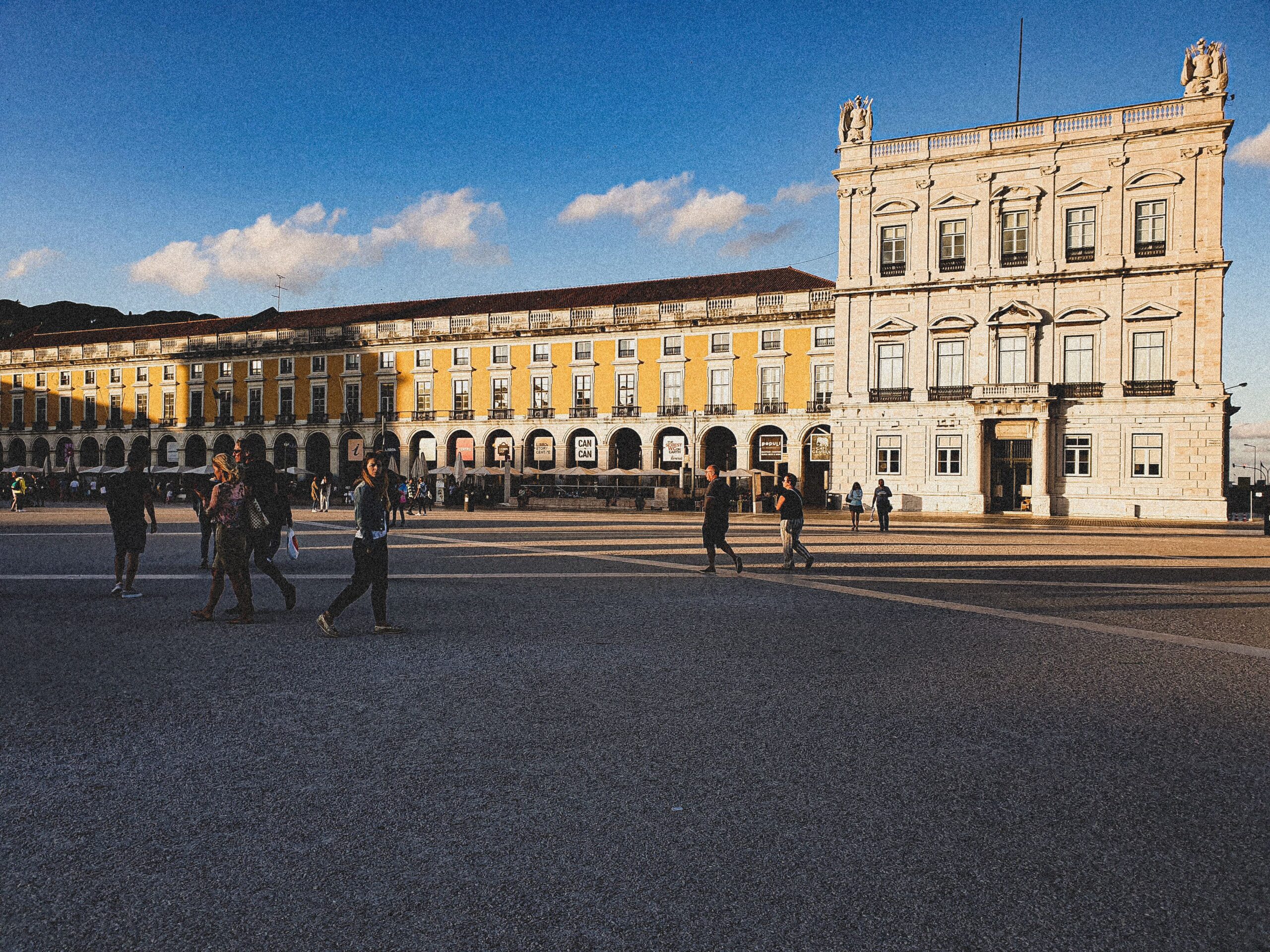 People walking on Praca do Comercio located in Lisbon, Portugal, on a sunny day.